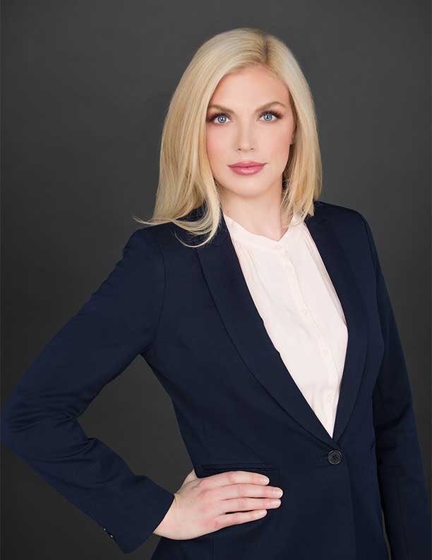 corporate headshot of woman with hand on hip not smiling